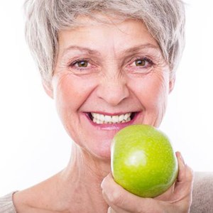 Older woman eating a green apple