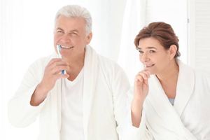 Older man and woman brushing teeth
