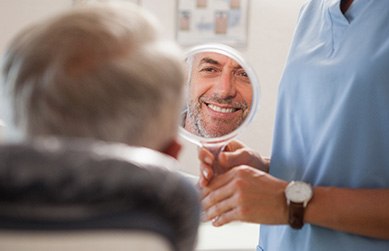 Man smiling at reflection in handheld mirror