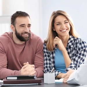 A happy couple talking to a dentist