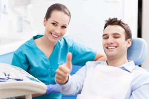 Smiling man in dental chair giving thumbs up