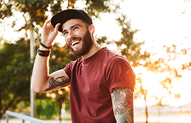 Young man with tattoo sleeves smiling in the sun