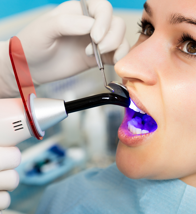 Dental patient having an ultraviolet light applied to her tooth