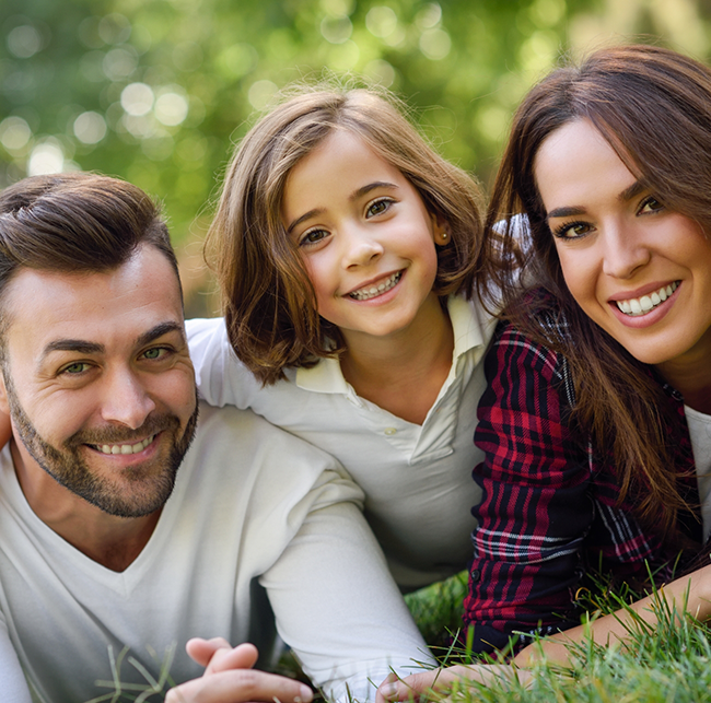 Family of three smiling outdoors after seeing a Delta Dental dentist in Sparks