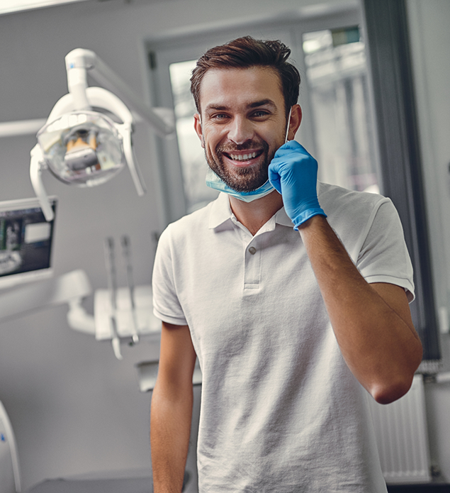 Smiling man pulling aside his face mask in a dental office