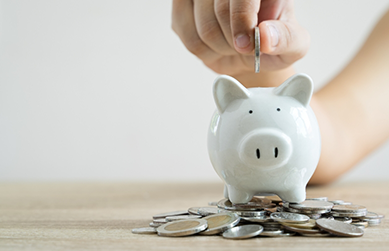Person putting coins into a piggy bank