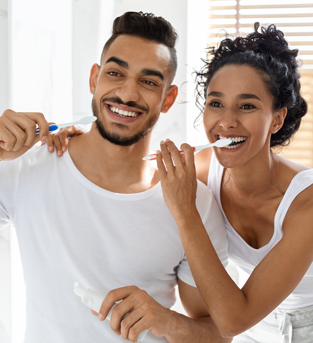 Man and woman brushing their teeth together at home