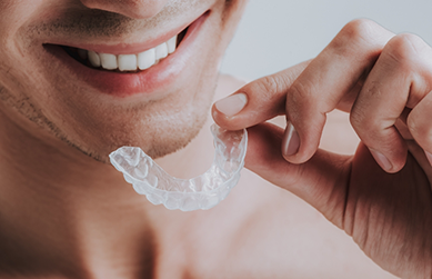 Man holding a mouthguard near his smile