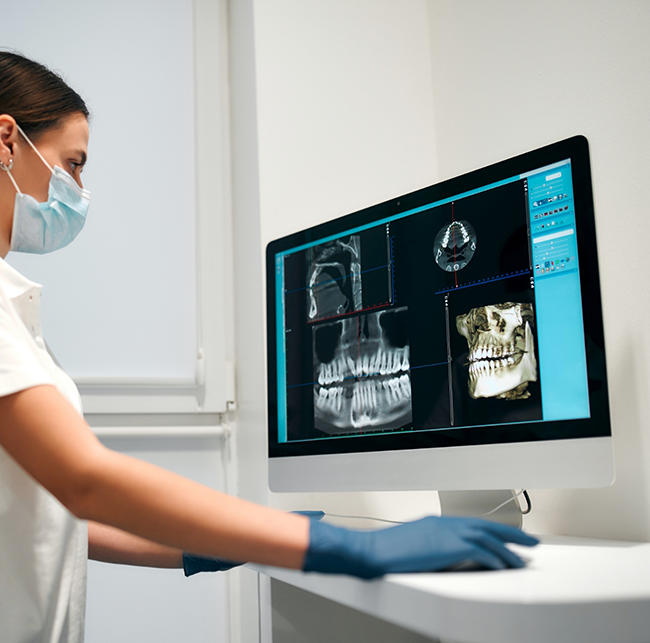 Dentist looking at a patient's x-rays of their teeth on a computer