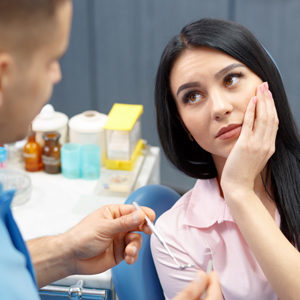 Woman in dental chair holding jaw