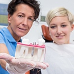 Dentist showing patient a comparison of implants and tooth structure