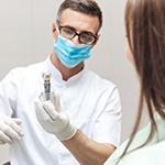 Dentist showing patient an implant model