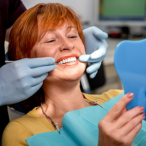 Older female patient looks at smile in mirror