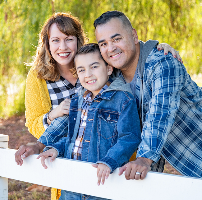 Family of three smiling in their yard after seeing a Humana dentist in Sparks