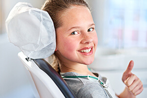 grinning young child flashing a thumbs up