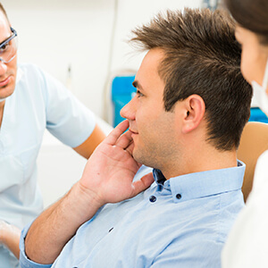 Man in dental chair holding cheek