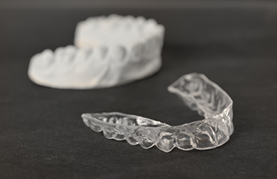 Clear aligner next to a mold of an arch of teeth