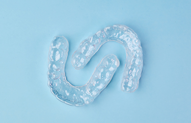 Two clear aligners on a light blue surface