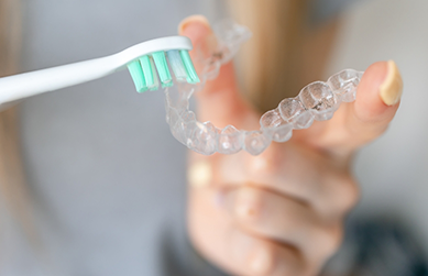 Person cleaning their aligner with a toothbrush