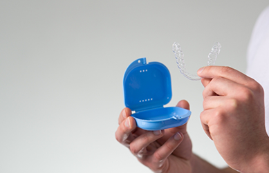 Person placing a clear aligner in its plastic case