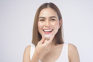 Happy woman holding her SureSmile aligner in Sparks