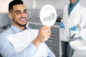 a man checking his veneers with a mirror