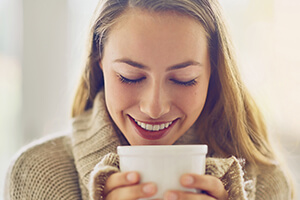 woman peering into mug enjoying her drink