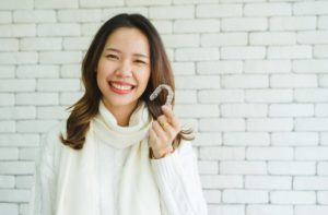 Woman holding Invisalign clear aligner