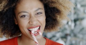 smiling woman biting into a candy cane 