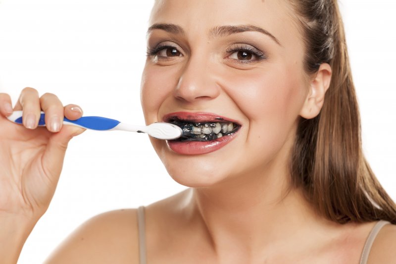 Woman brushing teeth with charcoal