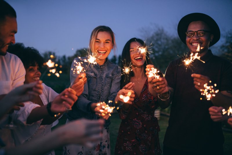 friends with healthy smiles holding sparklers