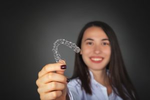 Woman holding clear aligner for SureSmile