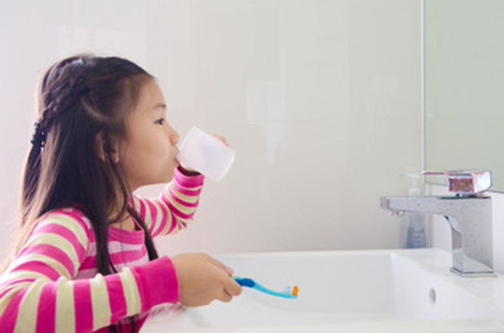 Girl rinsing after brushing her teeth.