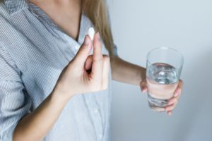 Woman holding medication and glass of water