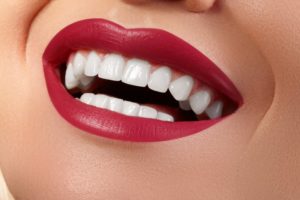 a woman wearing blue-red lipstick which shows off her white teeth