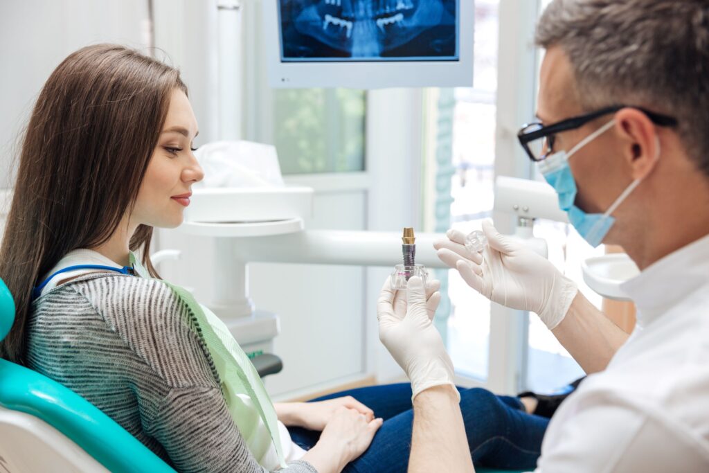 Dentist showing sample dental implant to patient