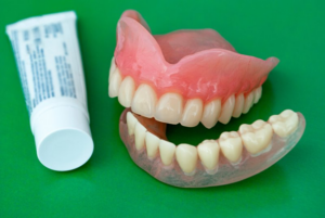 Tube of denture adhesive next to a pair of dentures