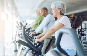Older people using treadmills at gym.