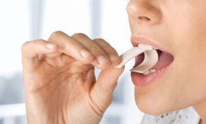 Person putting piece of chewing gum in their mouth.